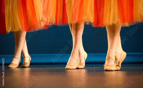 Legs of a trio of ballet dancers in red and yellow skirts