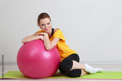 Portrait of beautiful young woman exercises with gym ball