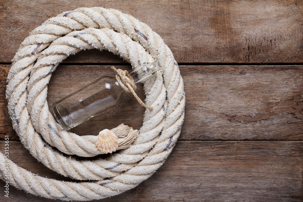 Obraz premium Sea rope with shell and message bottle on wooden table