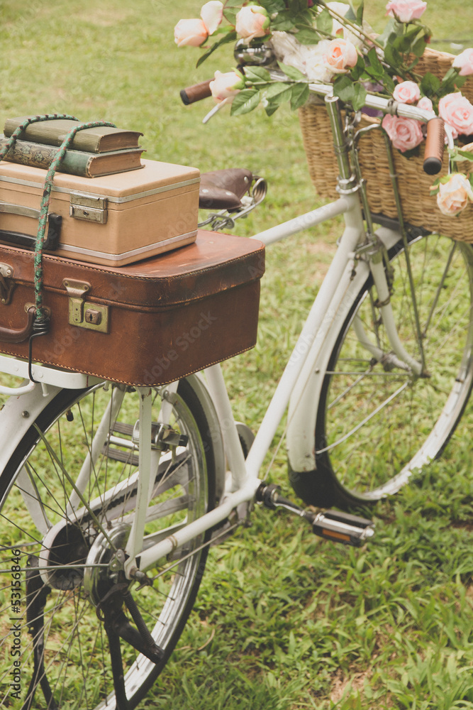 Naklejka premium Vintage bicycle on the field with a basket of flowers
