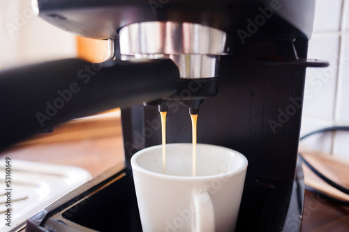 Closeup on coffee maker pouring hot espresso into a cup