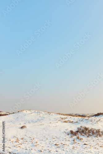 Snow winter dunes with blue sky. The Netherlands.