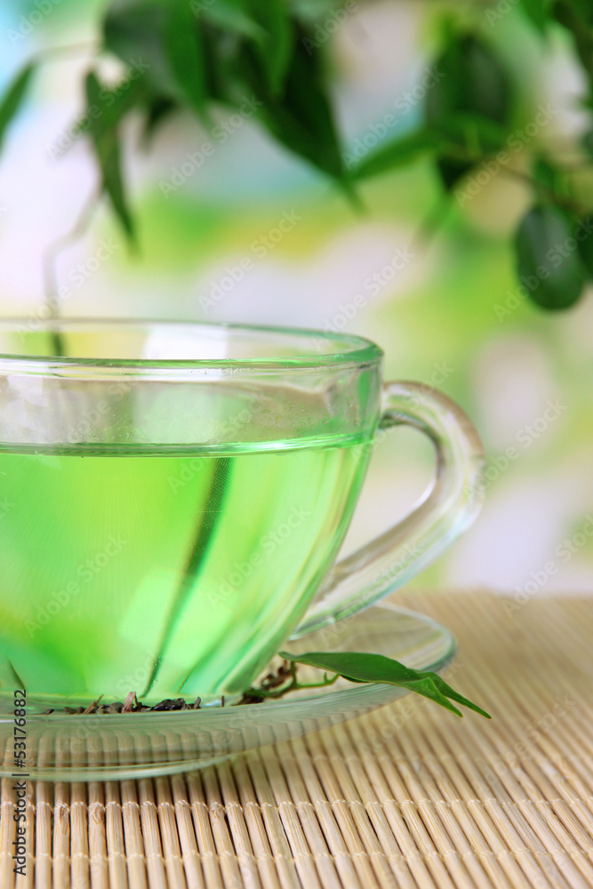 Transparent cup of green tea on bamboo mat, on nature Transparent cup of green tea on bamboo mat, on nature
