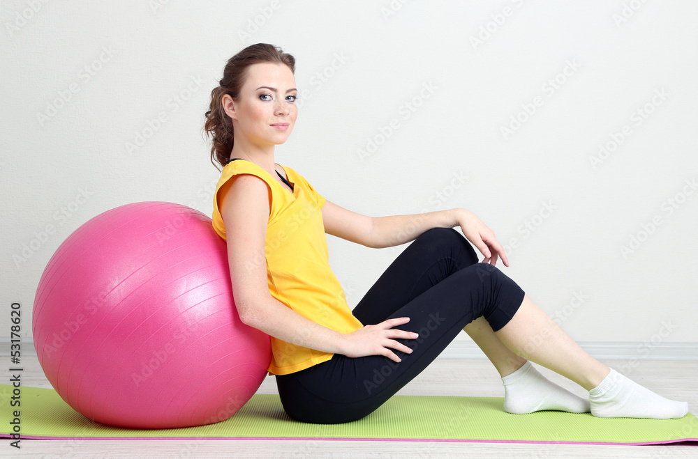 Naklejka premium Portrait of beautiful young woman exercises with gym ball