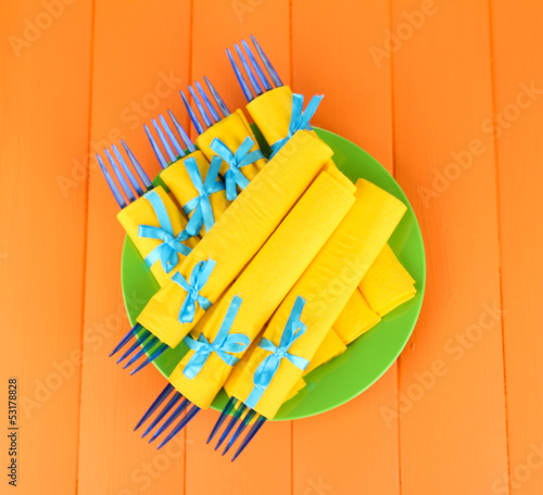 Blue plastic forks wrapped in yellow paper napkins 