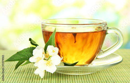 Cup of tea with jasmine, on bamboo mat, on bright background