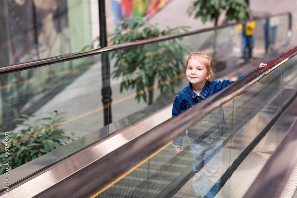Cute child in shopping center on moving escalator