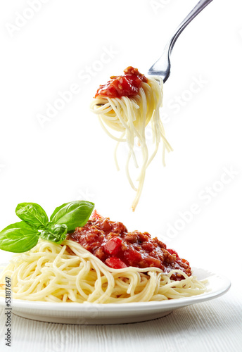 Spaghetti bolognese and green basil leaf on white plate