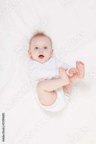 Cute baby with beautiful blue eyes lying in white bed