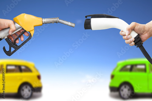 фотографія electric car and gasoline car concept. hand holding gas pump and