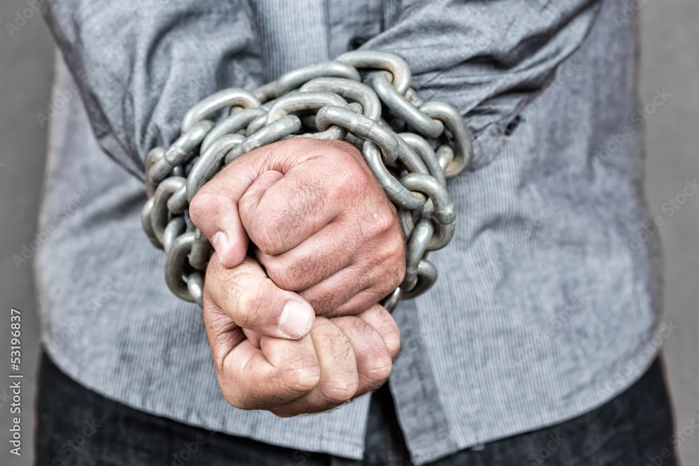 Close-up of a formally dressed man with his hands chained