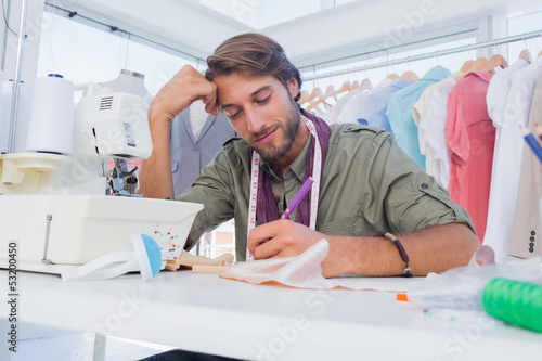 Smiling fashion designer working at his desk