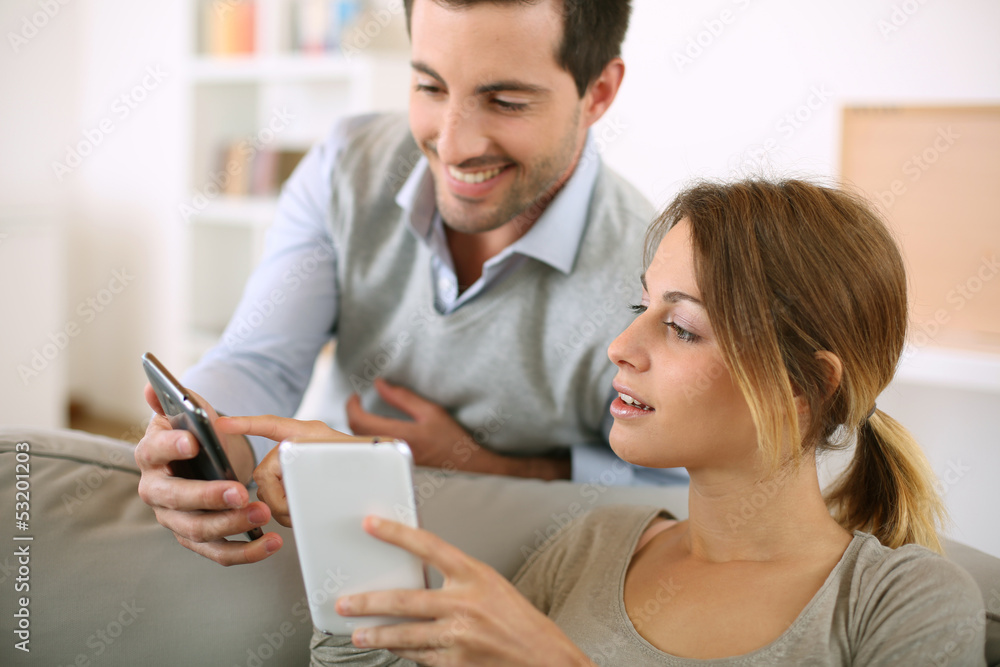 Young couple using smartphone at home