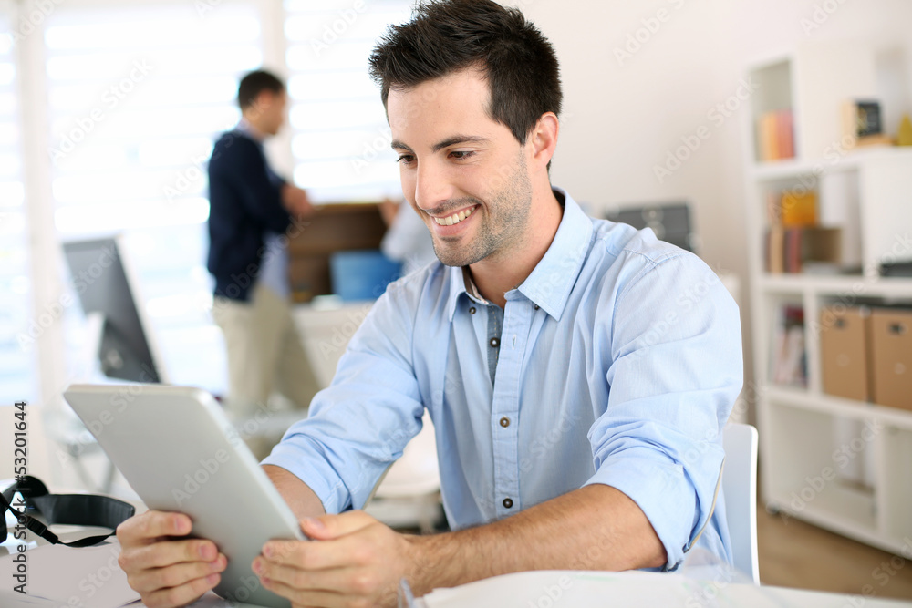 Smiling man in office working on digital tablet Smiling man in office working on digital tablet