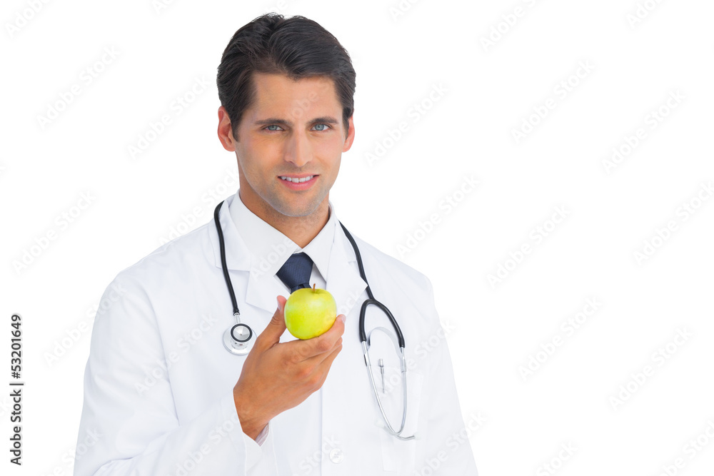 Fototapeta premium Doctor holding an apple and smiling at camera