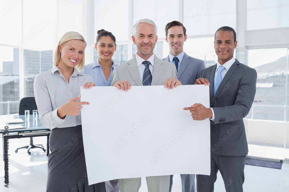 Business team holding large blank poster and pointing to it Business team holding large blank poster and pointing to it