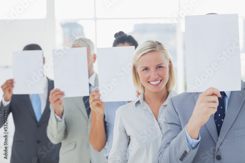 Business team covering face with white paper except for one woma