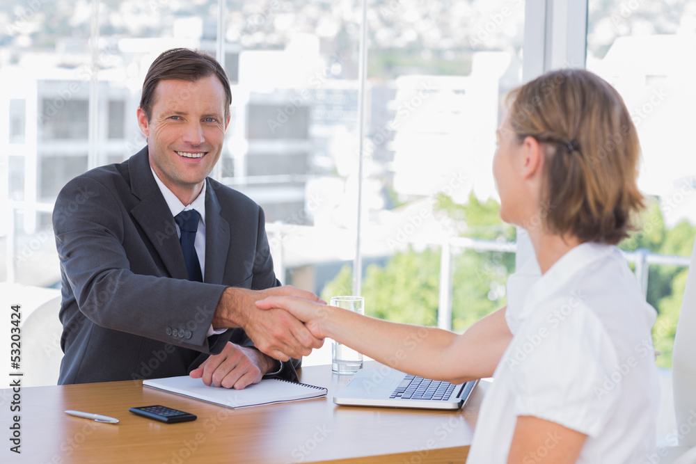 Smiling businessman shaking hand of a job applicant Smiling businessman shaking hand of a job applicant