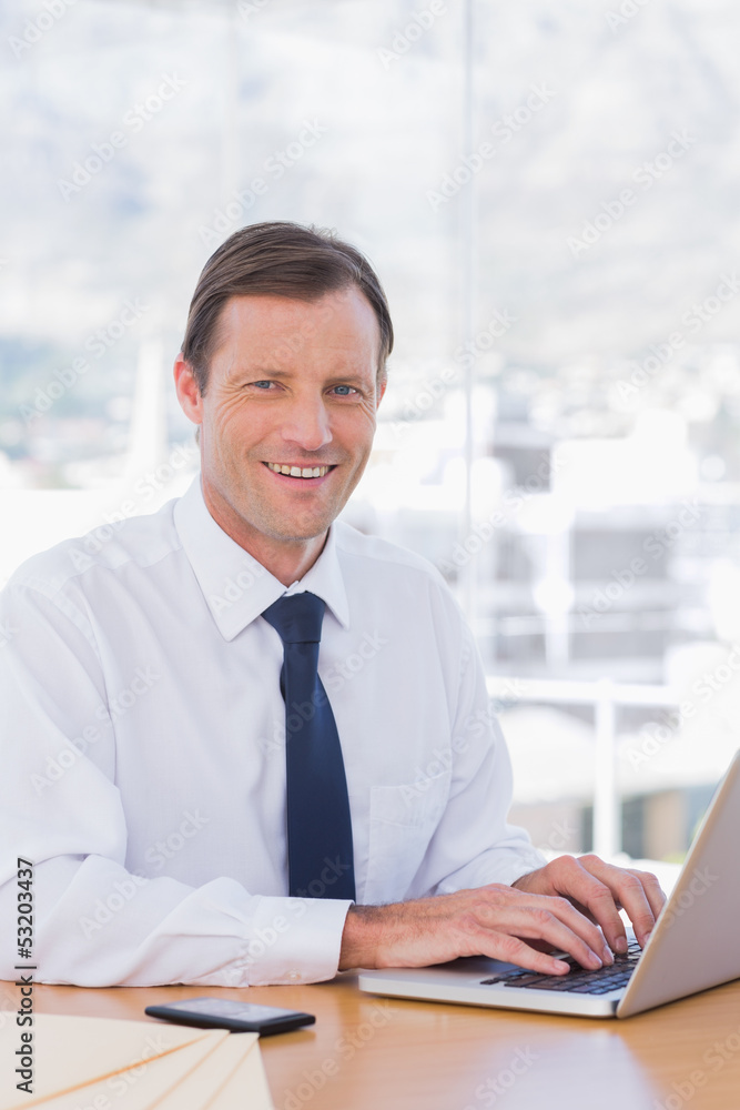 Smiling businessman working with his laptop