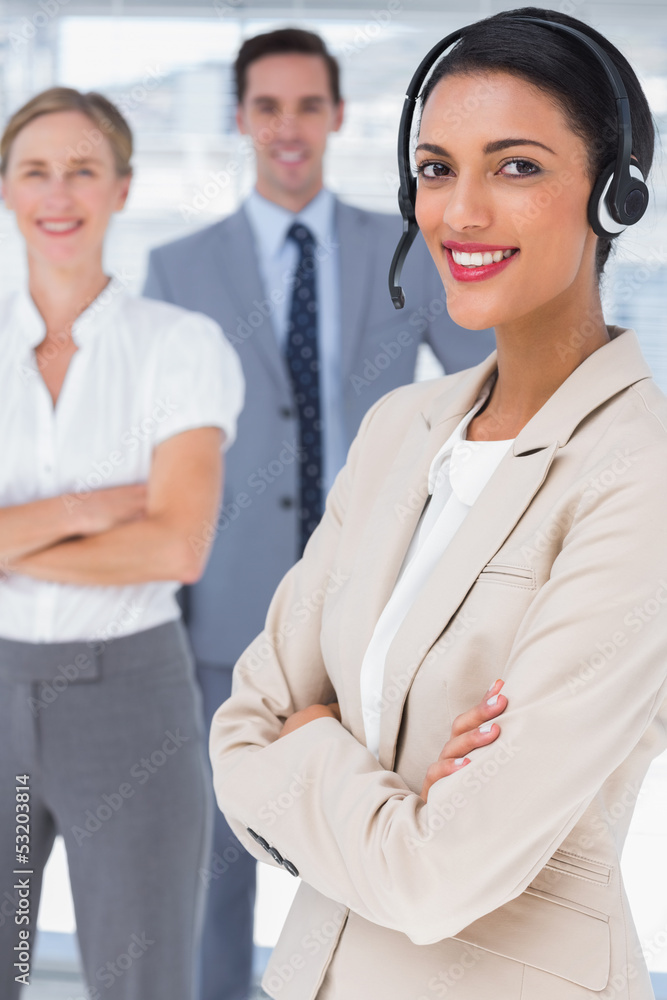 Fototapeta premium Smiling businesswoman with headset crossing her arms