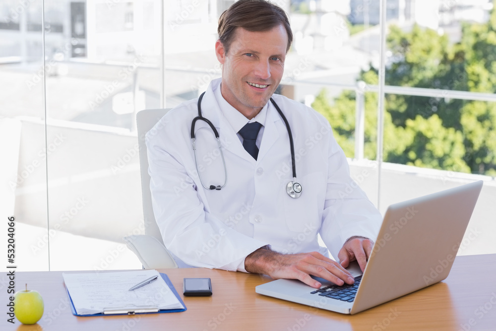 Smiling doctor working on a laptop Smiling doctor working on a laptop
