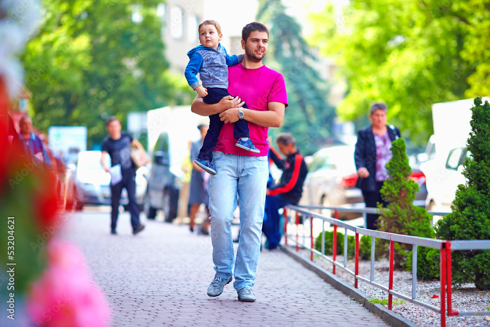 candid image of father with son walking the street candid image of father with son walking the street