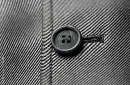 Close-up photograph of a black button on gray material.