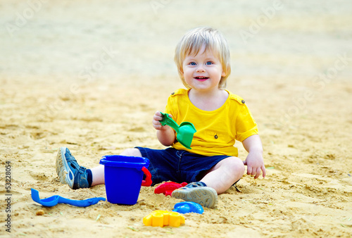 Canvas Print Adorable toddler playing with his toys in the sandpit