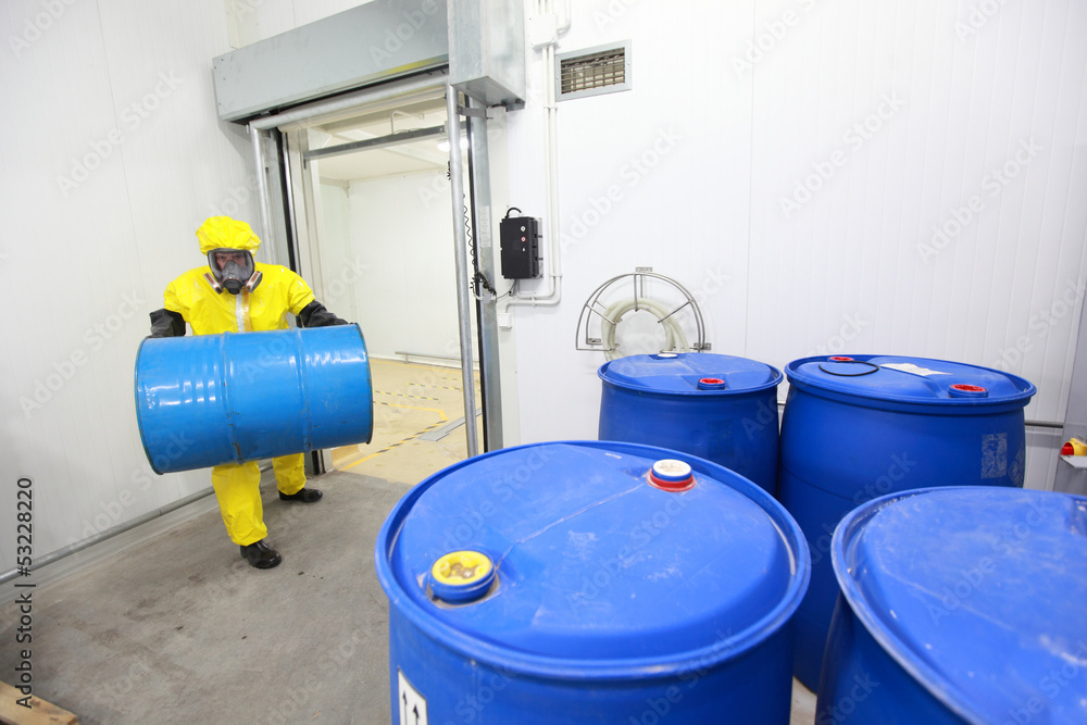 Worker in protective uniform, carrying blue barrel Worker in protective uniform, carrying blue barrel
