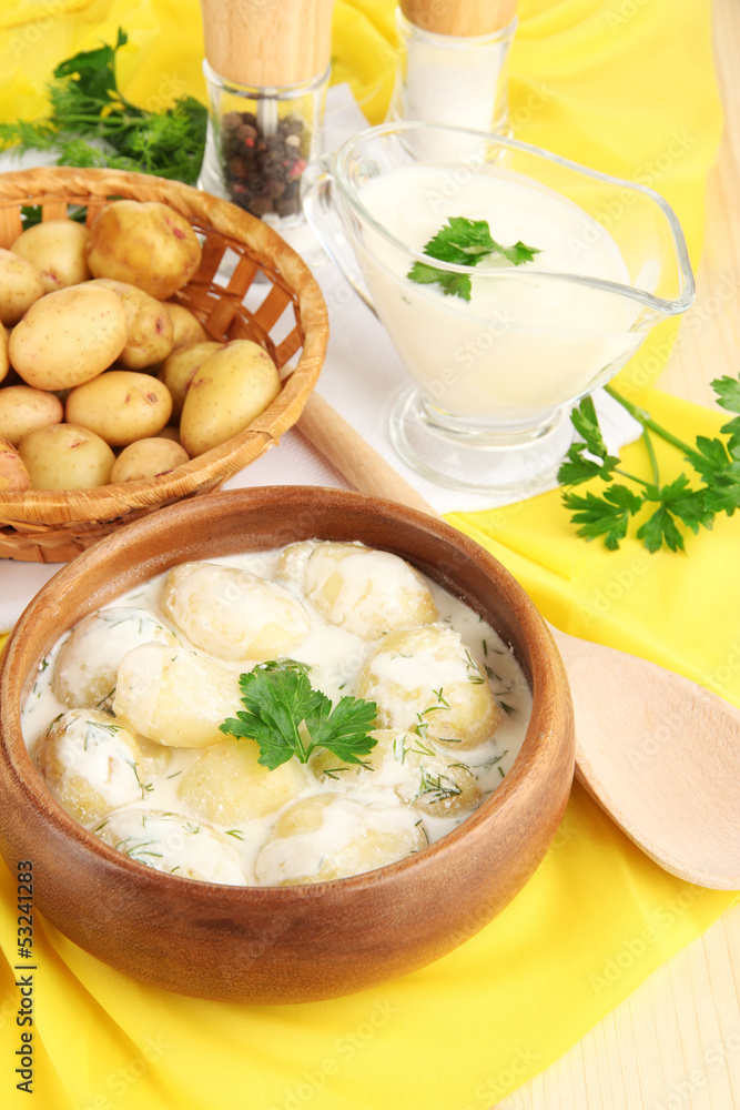 Tender young potatoes with sour cream and herbs in wooden bowl Tender young potatoes with sour cream and herbs in wooden bowl