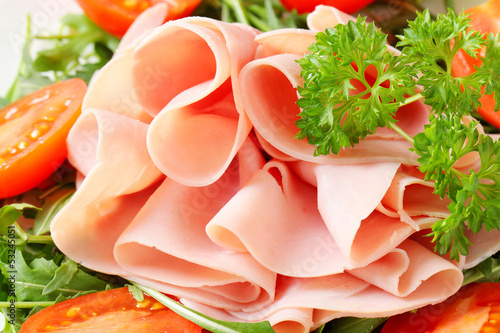 Sliced ham with arugula leaves and tomatoes