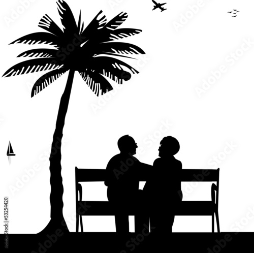 Lovely retired elderly couple sitting on bench on the beach