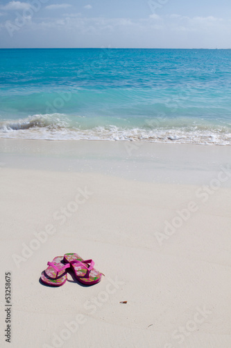 Pair of colored sandals on a white sand beach