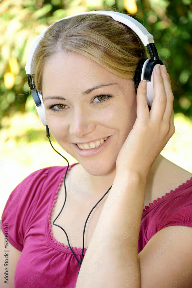 Junge Frau entspannt im Garten und hört Musik Junge Frau entspannt im Garten und hört Musik
