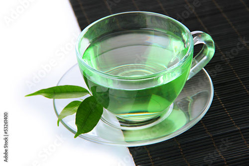 Transparent cup of green tea on bamboo mat, isolated on white