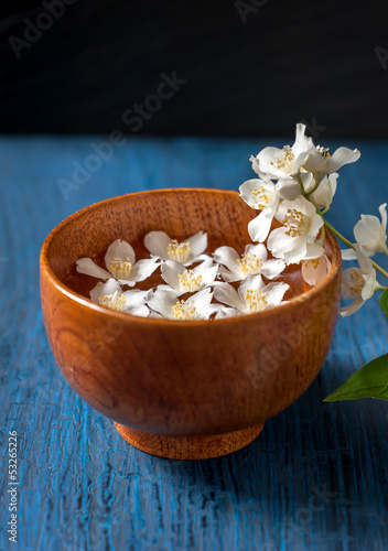 Spa. White flowers in a bowl of water on a blue vintage board