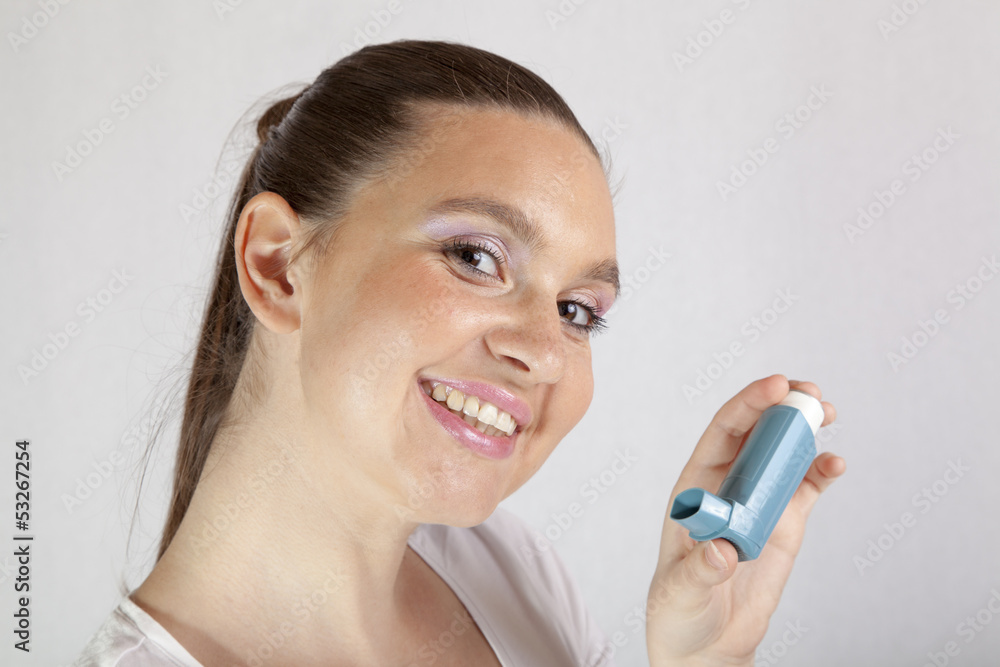 Cute smiling girl using an asthma inhaler for preventing attacks Cute smiling girl using an asthma inhaler for preventing attacks