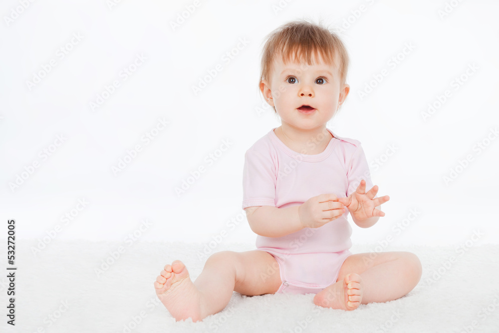 Baby is sitting on floor, on a gray background Baby is sitting on floor, on a gray background