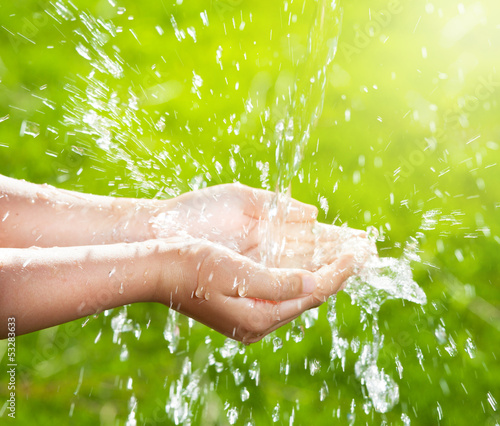 Stream of clean water pouring into children's hands photo