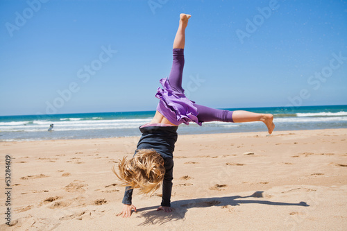 Young girl doing cartwheel at beach photo