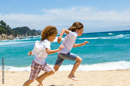 Two boys running on beach.