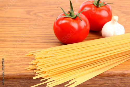 uncooked spaghetti, garlic and tomatos on a preparation board