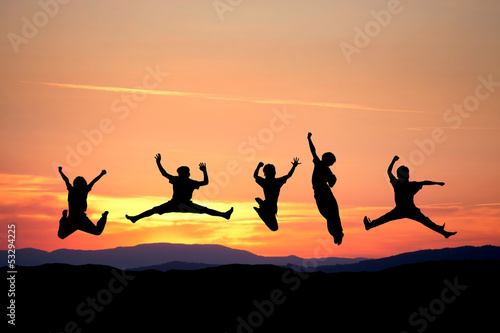 silhouette of kids jumping in sunset on hill