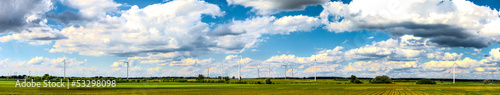 Wind power plants on field panorama