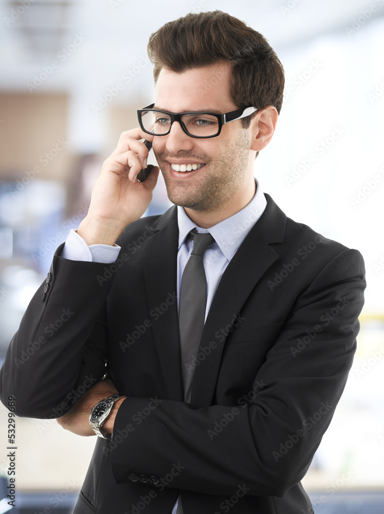 Smiling businessman talking on a mobile phone. Smiling businessman talking on a mobile phone.
