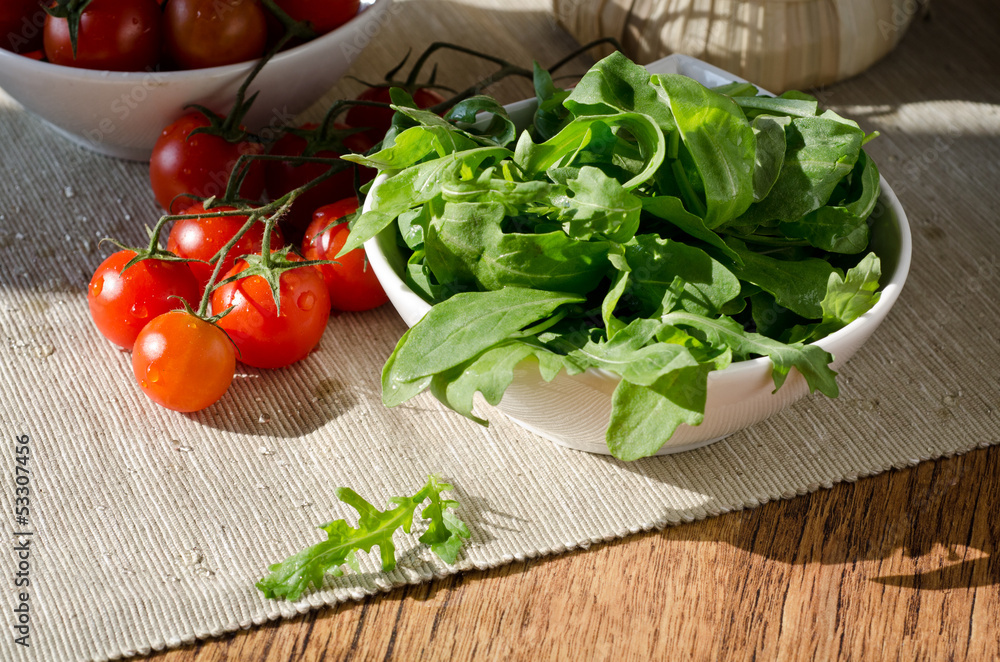 bowl of fresh green, natural arugula and red cherry tomatoes bowl of fresh green, natural arugula and red cherry tomatoes