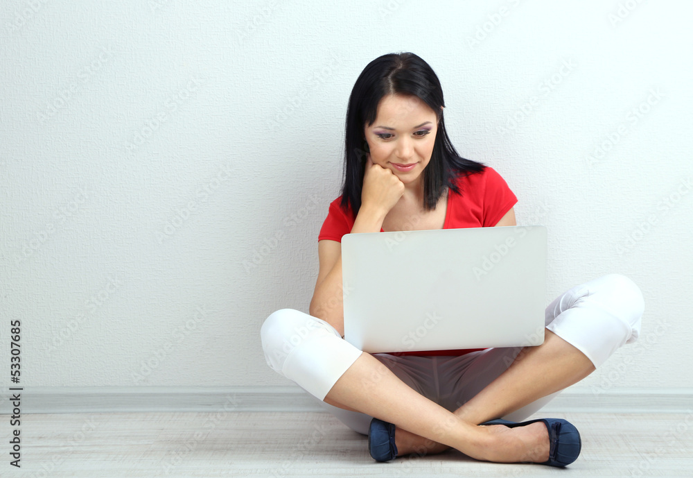 Beautiful young woman sitting with notebook in room Beautiful young woman sitting with notebook in room