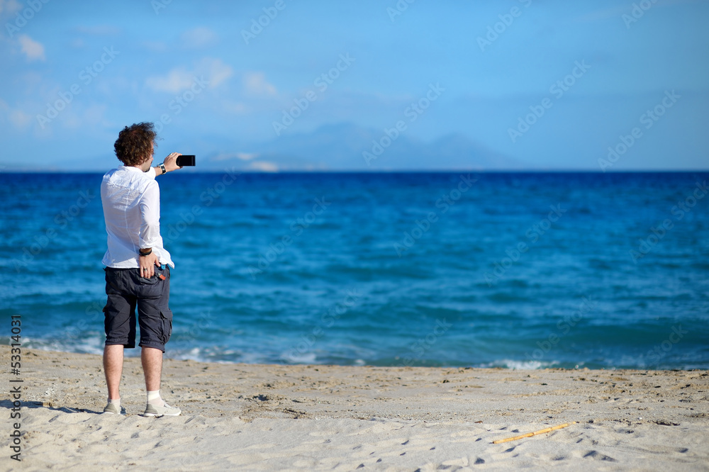 Man taking photo with cell phone on the beach