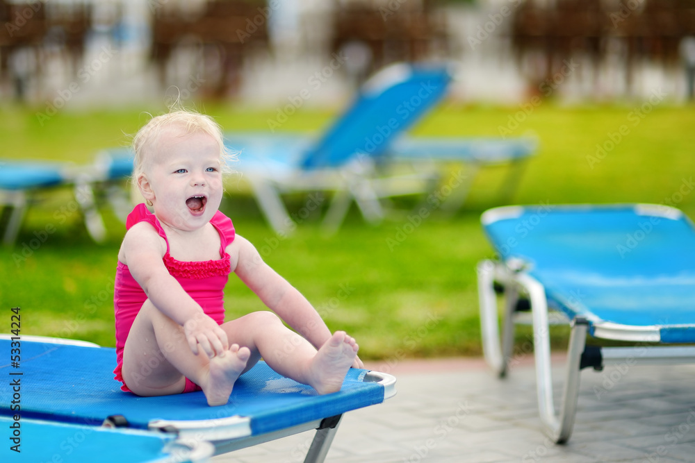 Adorable toddler girl sitting on a sunbed Adorable toddler girl sitting on a sunbed