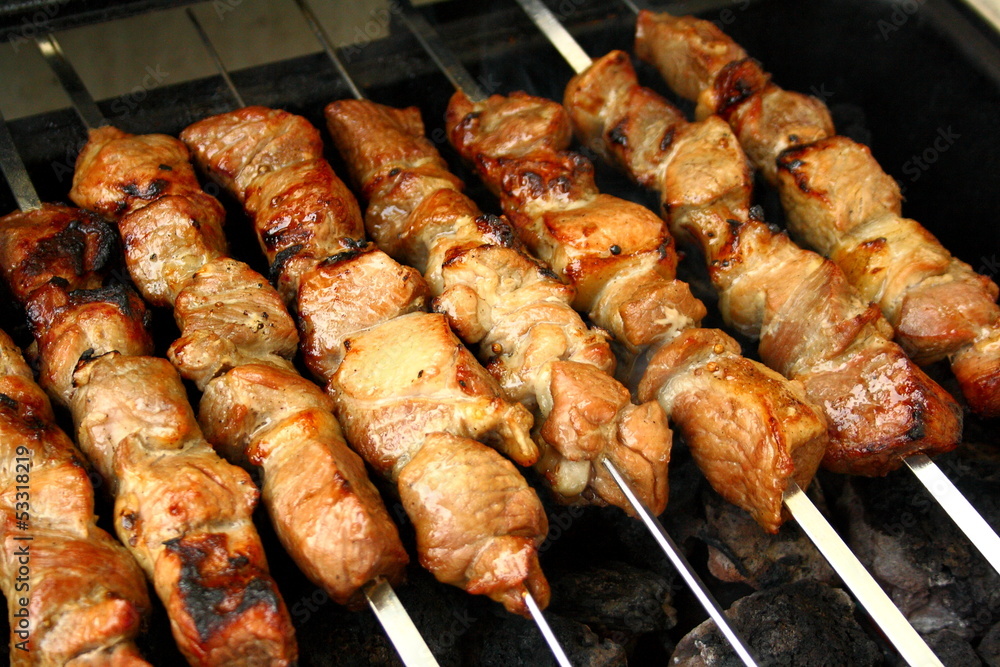 Marinated lamb grilling on metal skewer, close up